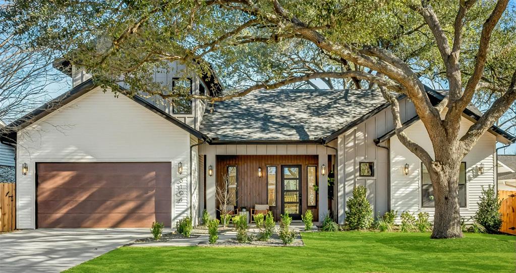 Cream farmhouse-style home in Allandale shaded by a large, mature oak tree, with a brown garage door, wood front door, and manicured front lawn