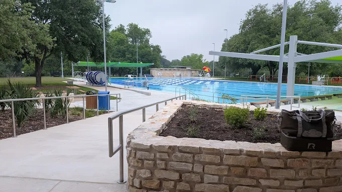 Renovated outdoor lap pool at Beverly S. Sheffield Northwest District Park in Austin, with a stone planter and shaded walkway in the foreground