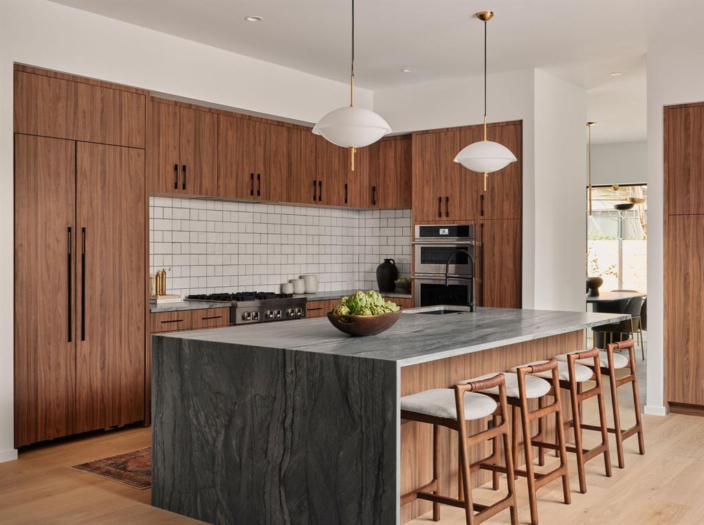 Kitchen in a newly built Allandale home with walnut cabinetry and a dark stone waterfall island