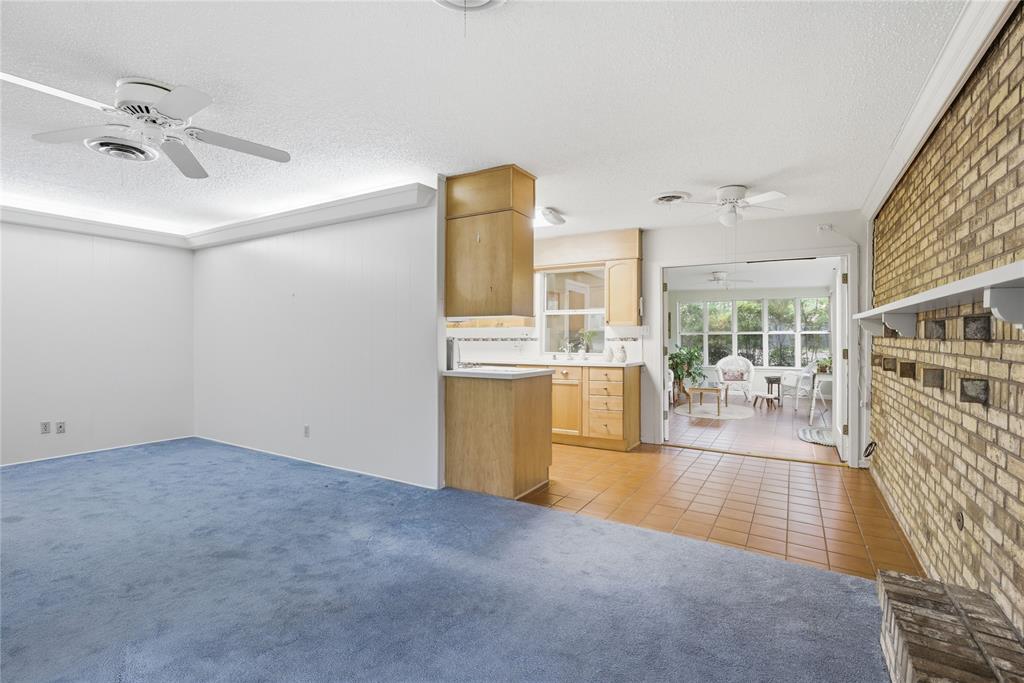 Original living room in an Allandale home with blue carpet, a brick accent wall, and a popcorn ceiling