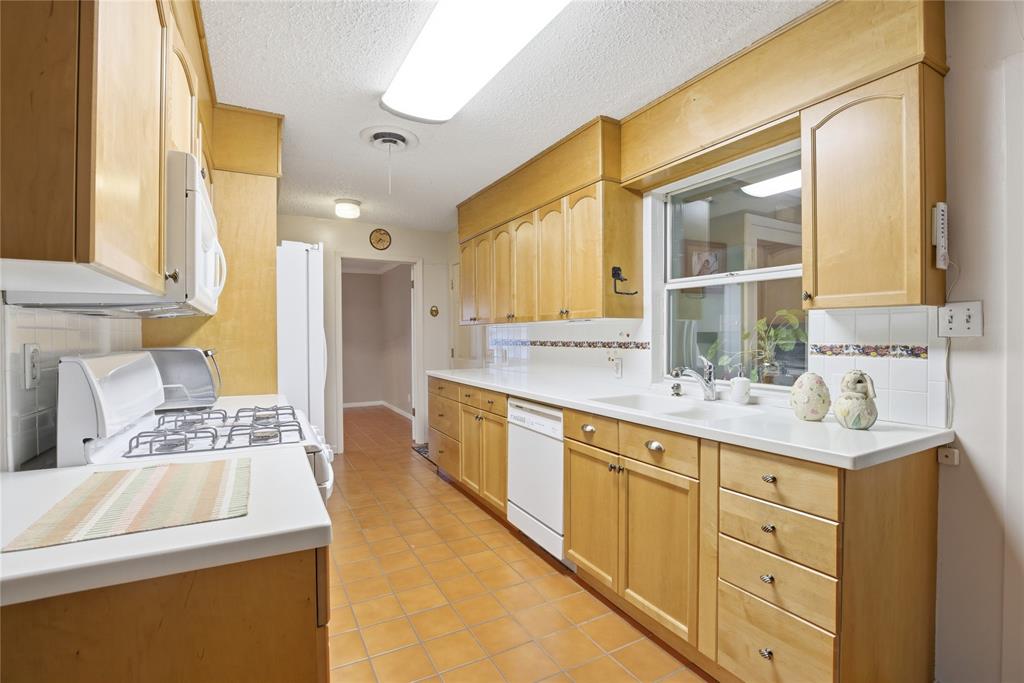 Original, unrenovated kitchen in an Allandale home with light wood cabinets and tile countertops