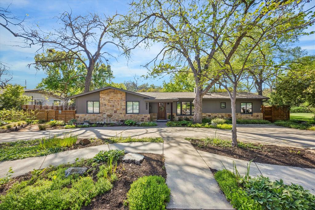 Remodeled one-story home in Allandale with updated stone and dark siding and modern landscaping